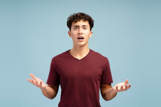Excited, upset teen boy with open mouth looking at camera, standing isolated on blue background photo