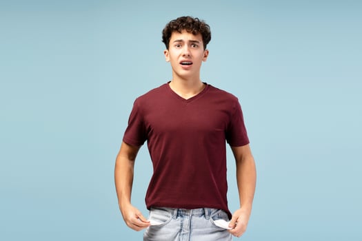 Portrait of sad, unhappy teen boy wearing casual clothes showing empty pockets photo