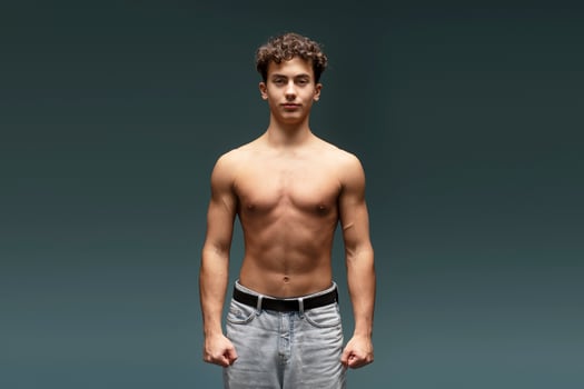 Confident, attractive teen boy with naked torso, bare body, looking at camera, fashion model photo