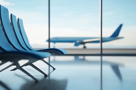 Three chairs in an airport waiting room with an airplane photo