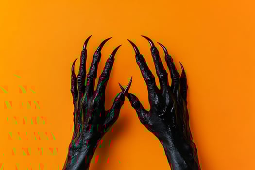 Hands of a black woman with claws on an orange background photo