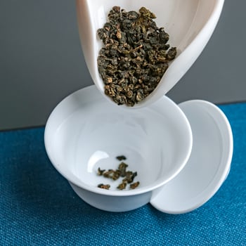 Pouring Oolong Tea Leaves into Gaiwan for Brewing, a ritual that encompasses beauty and tradition photo