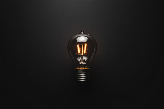 A Single Illuminated Light Bulb Against a Dark Background photo