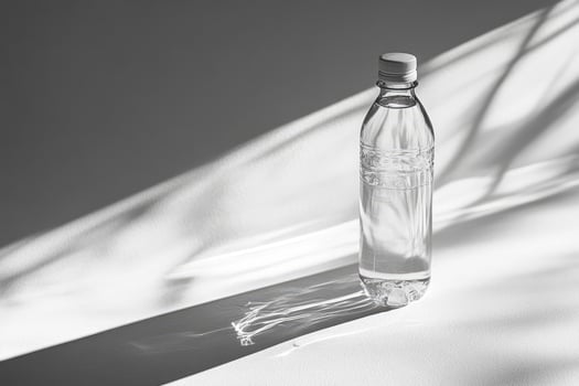 A Clear Plastic Bottle of Water on a White Surface with a Shadow photo