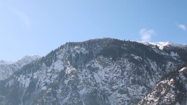 Snowy Mountain Ridge with Evergreen Trees with Sunlight in Day and a Clear Blue Sky in Kalam, Pakistan photo