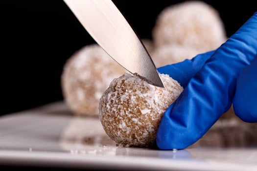 Beautiful sweets with coconut are cut with a knife on a white plate on a black background photo