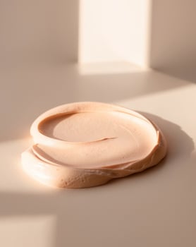 Creamy texture applied on a surface in bright light showcases a subtle peach color photo