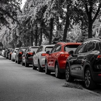 Parked cars line suburban road, bordered by trees with blurred background emphasizing vehicles For Social Media Post Size photo