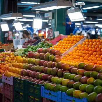 Market stall displays vibrant mangoes and oranges, illuminated, indoor fresh produce scene For Social Media Post Size photo