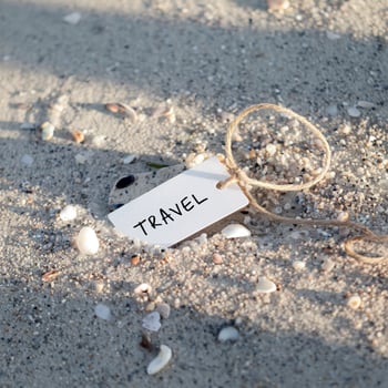 Small tag labeled Travel buried in sand, scattered shells under sunlight For Social Media Post Size photo