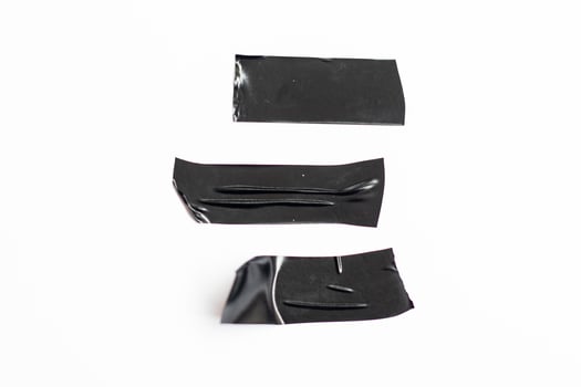 Piece of torn black ribbon isolated on white background. A set of crushed plastic adhesive tape photo