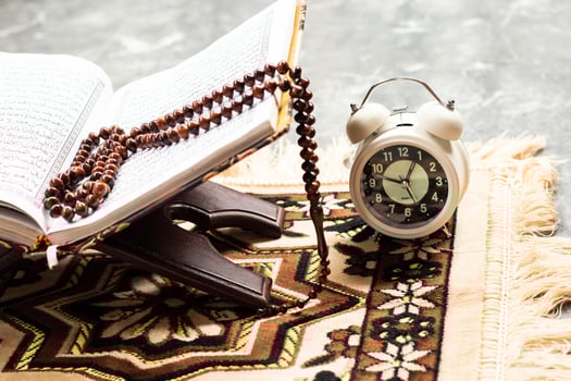 Islamic Holy Book Quran with rosary beads and reminder clock Ramadan Concept. photo