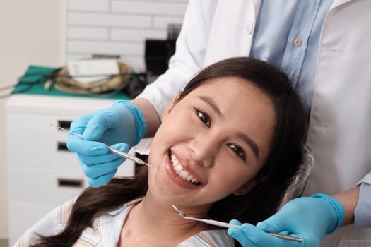 Close-up shot of beautiful Asian female face, white teeth, and cheerful face in dentist's hand, dental treatment with tooth whitening and cleaning in doctor hospital clinic, oral hygiene healthcare. photo