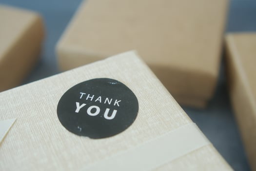 hand putting a thank you sticker on a gift box photo