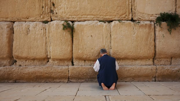 A man kneeling down in front of a wall photo