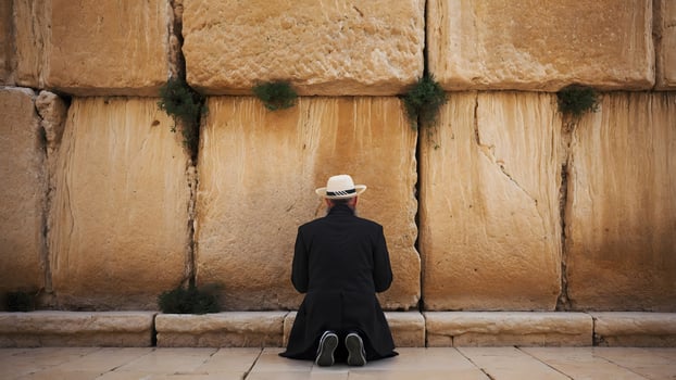 A man in a hat is praying at the western wall photo