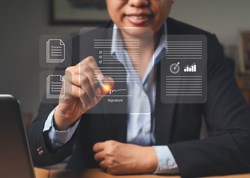 A businesswoman uses a pen to sign electronic documents on a virtual screen while sitting in the office photo