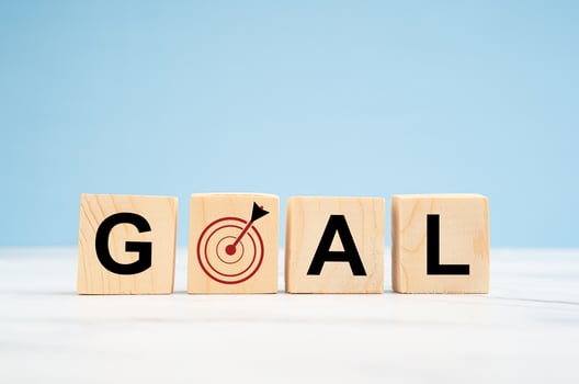 Business and goal concept. Wooden cubes with the letters G, A, L, and target icon on a marble table against a blue background photo