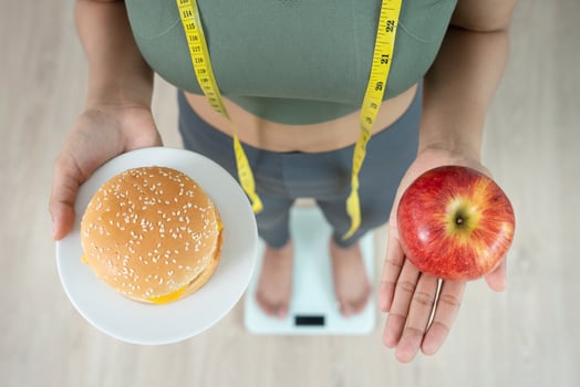 Beauty slim female body choose during hamburger and apple. Woman achieves weight loss goal for healthy life, crazy about thinness, thin waist, nutritionist. Diet, body shape. photo