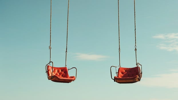 Two empty swings against a clear blue sky. photo