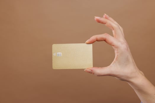 Hand holding credit gold card on beige gold background. photo