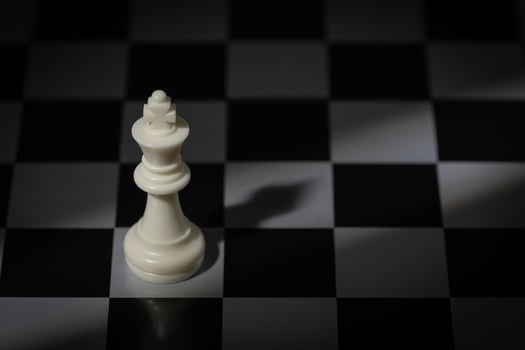 A close-up of a chessboard highlighting the white KING standing out among black pieces, symbolizing strategic thinking, leadership, and decisive planning in overcoming challenges and achieving goals. photo