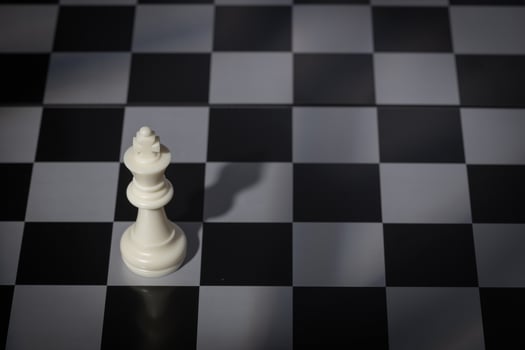 A close-up of a chessboard highlighting the white KING standing out among black pieces, symbolizing strategic thinking, leadership, and decisive planning in overcoming challenges and achieving goals. photo