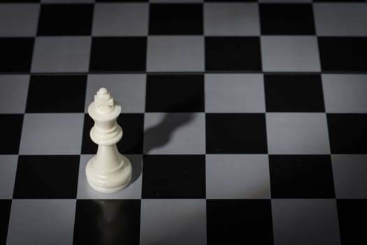 A close-up of a chessboard highlighting the white KING standing out among black pieces, symbolizing strategic thinking, leadership, and decisive planning in overcoming challenges and achieving goals. photo