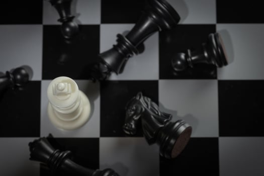 A close-up of a chessboard highlighting the white KING standing out among black pieces, symbolizing strategic thinking, leadership, and decisive planning in overcoming challenges and achieving goals. photo