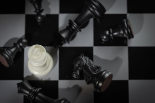 A close-up of a chessboard highlighting the white KING standing out among black pieces, symbolizing strategic thinking, leadership, and decisive planning in overcoming challenges and achieving goals. photo