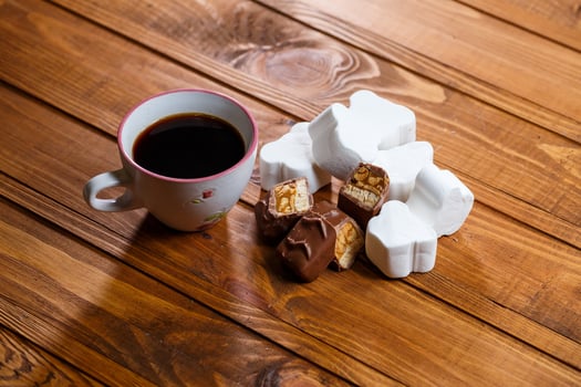 white cup of black coffee, chocolate with nuts on a wooden board with marshmallows photo