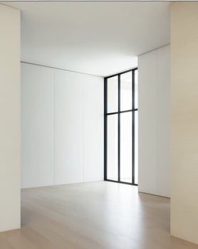 A large living room with a white wall and a large window photo