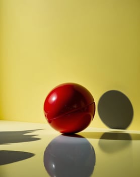 Bright yellow background with a red ball creating playful shadows and reflections photo