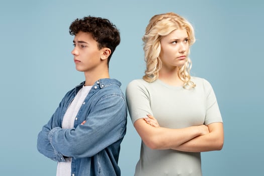 Sad quarreling couple, young guy and girl with crossed arms standing looking away photo
