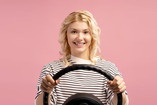 Portrait of stylish, smiling blonde teenager, happy girl holding steering wheel, driver photo
