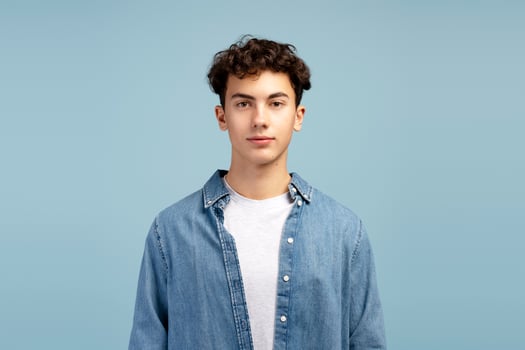 Portrait of serious, handsome boy wearing casual clothes, isolated on blue background photo
