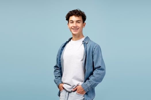 Portrait of happy teenager boy wearing casual clothes, white t shirt and shirt on blue background photo