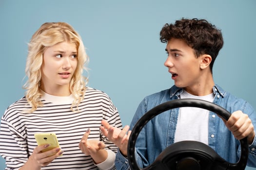 Boyfriend and girlfriend having conflict, boy holding steering wheel, girl holding mobile phone photo