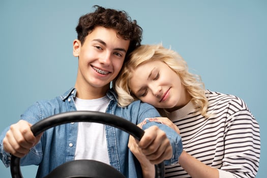Smiling boy and girl with closed eyes, boyfriend holding helm, posing isolated on blue background photo