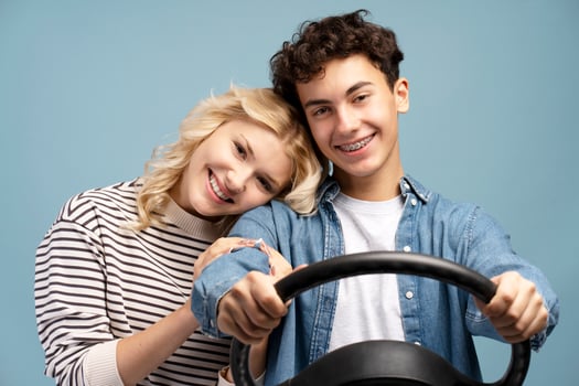 Happy beautiful couple attractive boy and girl male driver holding steering wheel, looking at camera photo