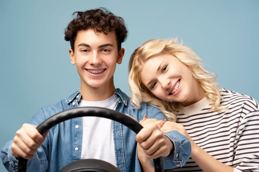Portrait of happy, smiling couple, attractive boy and girl, male driver holding steering wheel photo