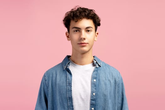 Portrait of happy, attractive, handsome boy wearing casual clothes isolated on pink background photo