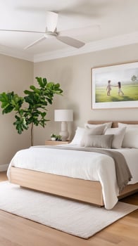 A bedroom with a bed, a painting and a plant photo
