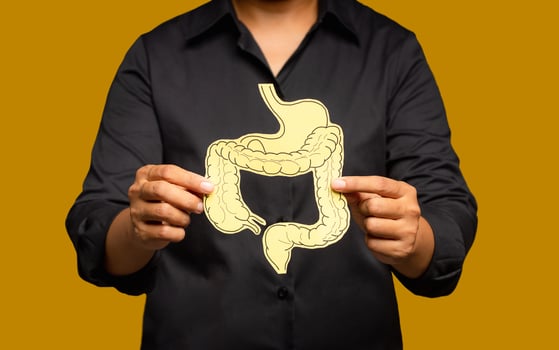 Close-up of hands holding a colon symbol while standing on a yellow background. photo