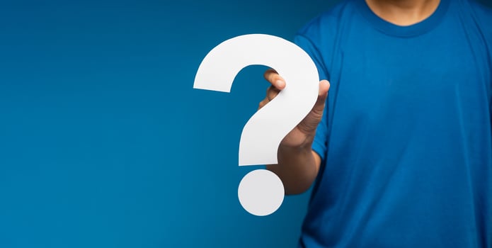 Businessman holding a white question mark paper while standing on a blue background photo