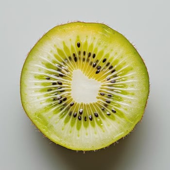 A slice of kiwi fruit cut in half to reveal its inner flesh and seeds. photo