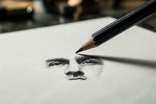 An intricate pencil sketch of a human face is in progress. A sharpened pencil is poised above the paper, capturing fine details in a well-lit creative workspace with art supplies around. photo