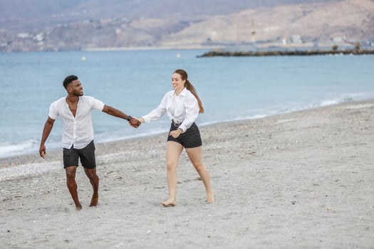 Couple enjoying a sunny day walking hand in hand along the sandy shores of Playa del Zapillo in Almeria, Spain photo