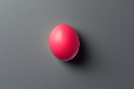 A single pink sphere rests on a grey surface photo