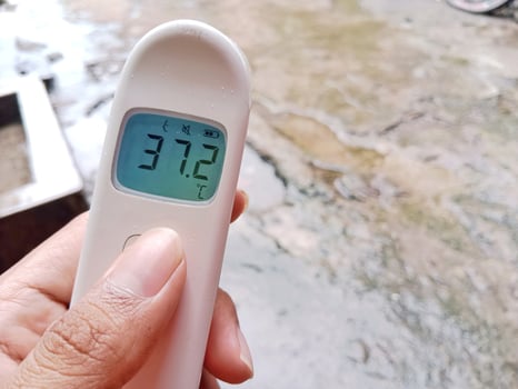 Slight Fever. Non contact digital medical infrared forehead thermometer shows 37.2 photo